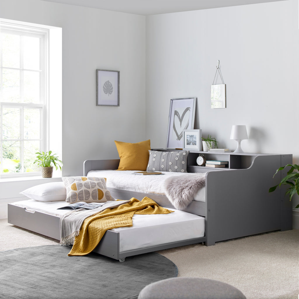 Tyler Pine Guest Bed With Trundle in grey. Shown in furnished room with trundle open & dressed.