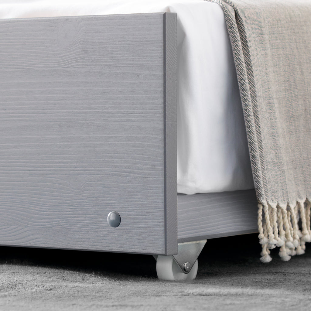 Tyler Pine Guest Bed With Trundle in grey. Shown in furnished room, castor detail