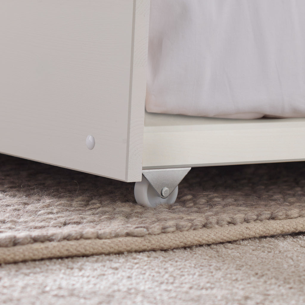 Tyler Pine Guest Bed With Trundle in white. Shown in furnished room, castor detail